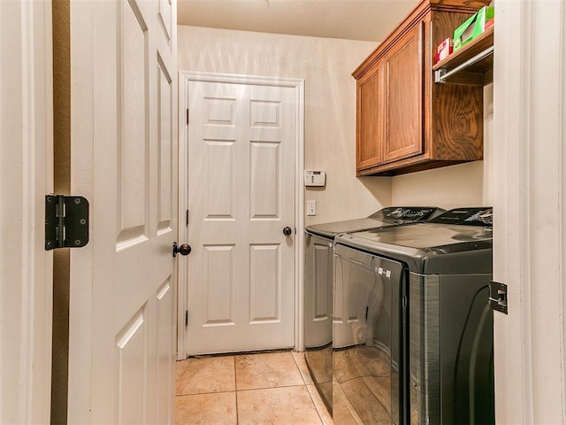 washroom featuring light tile patterned floors, washing machine and dryer, and cabinets