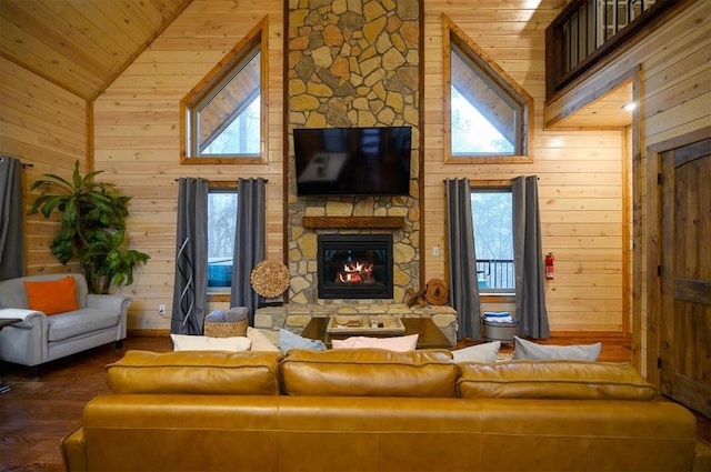 living room with a stone fireplace, plenty of natural light, high vaulted ceiling, and wood walls