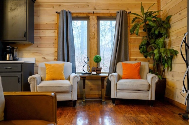 sitting room with dark hardwood / wood-style floors and wood walls