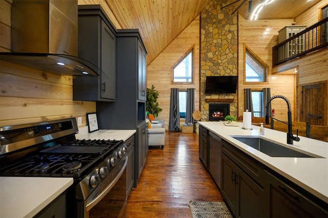 kitchen with wood walls, stainless steel range with gas cooktop, wooden ceiling, and wall chimney range hood