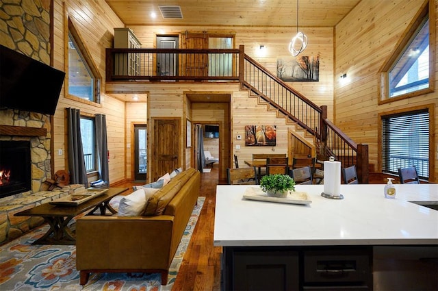 living room featuring a fireplace, wooden ceiling, a high ceiling, and wood walls