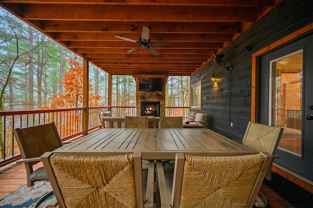 deck with exterior fireplace and ceiling fan