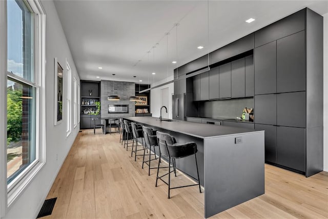 kitchen with light wood finished floors, visible vents, a sink, modern cabinets, and a kitchen bar