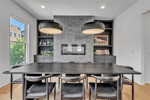 bar featuring built in shelves, baseboards, light wood-style floors, a bar, and decorative light fixtures