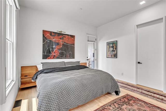 bedroom with multiple windows and wood finished floors