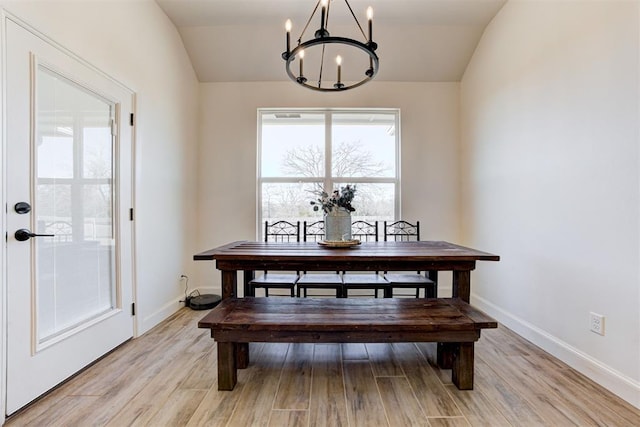 dining area featuring a notable chandelier, vaulted ceiling, and light wood-type flooring