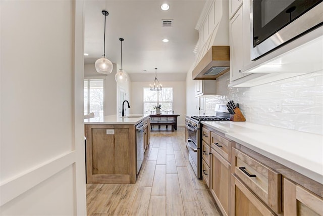 kitchen featuring sink, custom exhaust hood, tasteful backsplash, pendant lighting, and stainless steel appliances