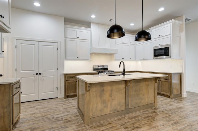 kitchen with white cabinetry, a kitchen island with sink, and built in microwave