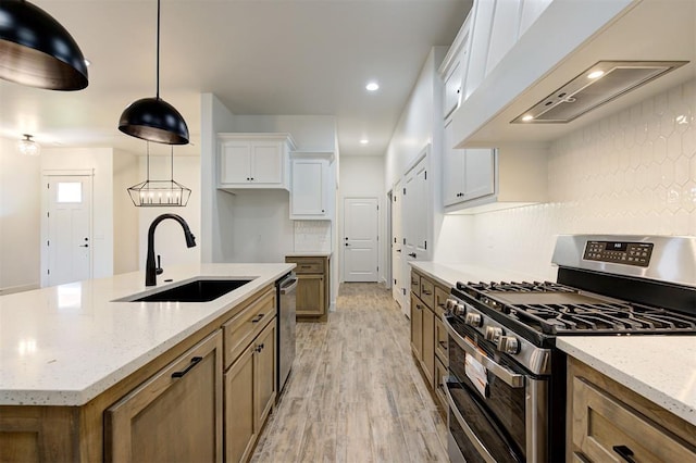 kitchen featuring appliances with stainless steel finishes, white cabinetry, sink, custom exhaust hood, and a center island with sink