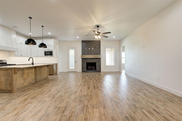 kitchen with white cabinetry, hanging light fixtures, light hardwood / wood-style flooring, appliances with stainless steel finishes, and ceiling fan