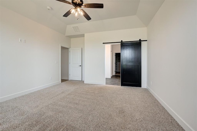 unfurnished bedroom featuring vaulted ceiling, a barn door, carpet floors, and ceiling fan