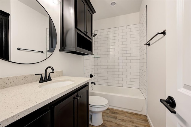 full bathroom with wood-type flooring, toilet, tiled shower / bath combo, and vanity