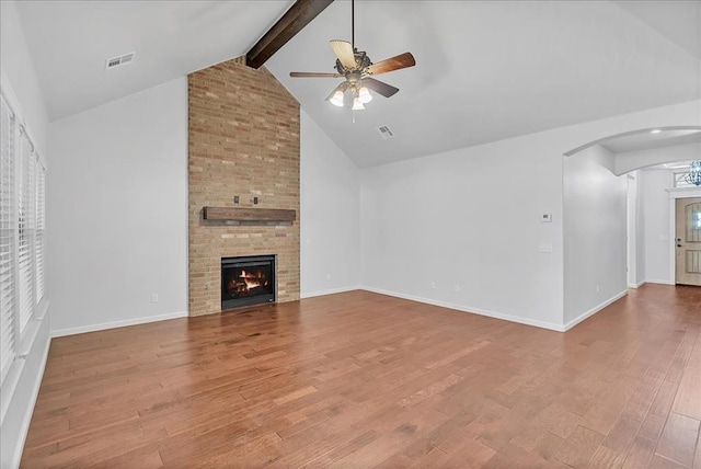 unfurnished living room featuring high vaulted ceiling, beamed ceiling, wood-type flooring, ceiling fan, and a brick fireplace