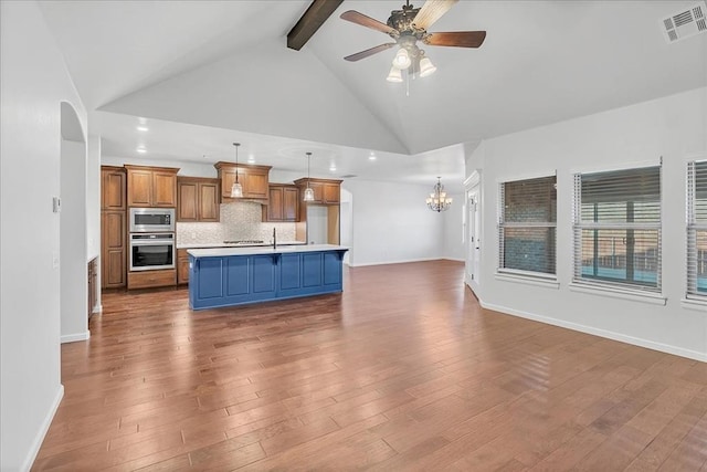 kitchen featuring pendant lighting, stainless steel appliances, an island with sink, and hardwood / wood-style flooring