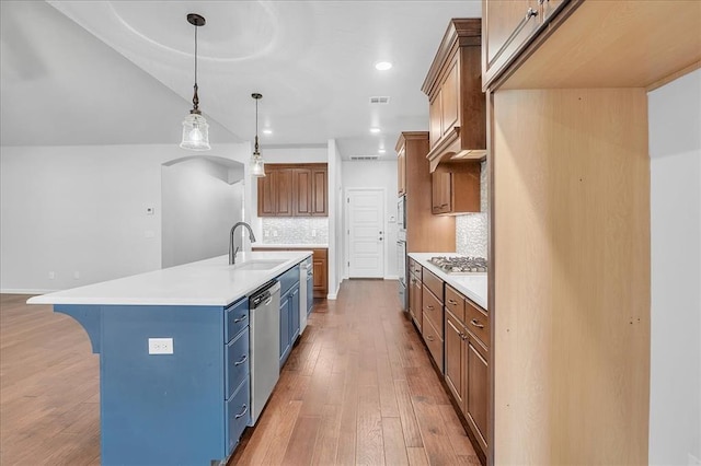 kitchen with pendant lighting, sink, light hardwood / wood-style flooring, a kitchen island with sink, and stainless steel appliances