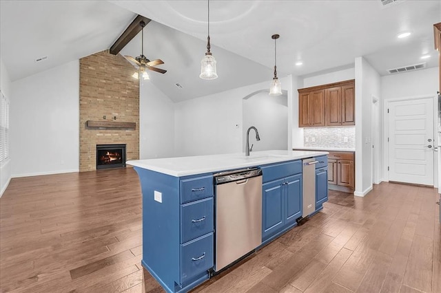 kitchen with sink, a kitchen island with sink, dark hardwood / wood-style floors, a large fireplace, and stainless steel dishwasher