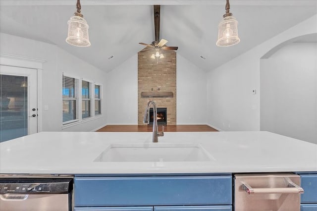 kitchen featuring stainless steel dishwasher, blue cabinets, a fireplace, and sink