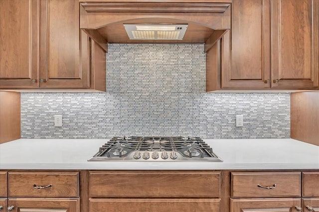 kitchen with tasteful backsplash, range hood, and stainless steel gas cooktop