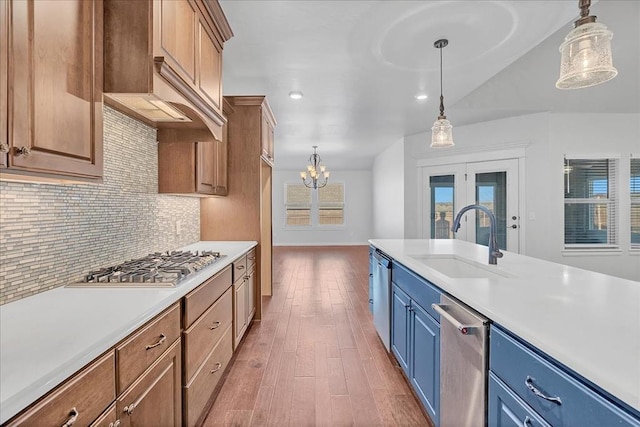 kitchen with appliances with stainless steel finishes, decorative light fixtures, sink, decorative backsplash, and hardwood / wood-style flooring