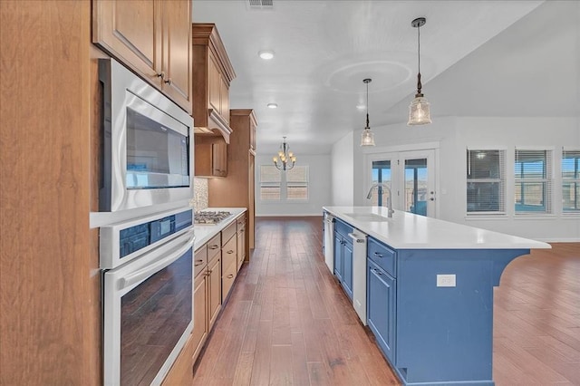 kitchen featuring sink, hardwood / wood-style flooring, hanging light fixtures, stainless steel appliances, and a center island with sink