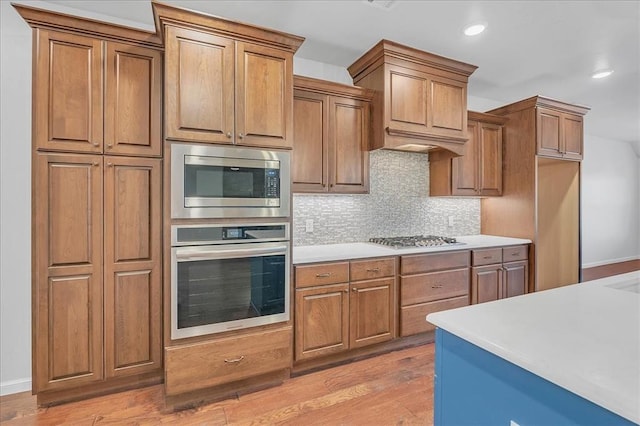 kitchen with tasteful backsplash, stainless steel appliances, and light wood-type flooring