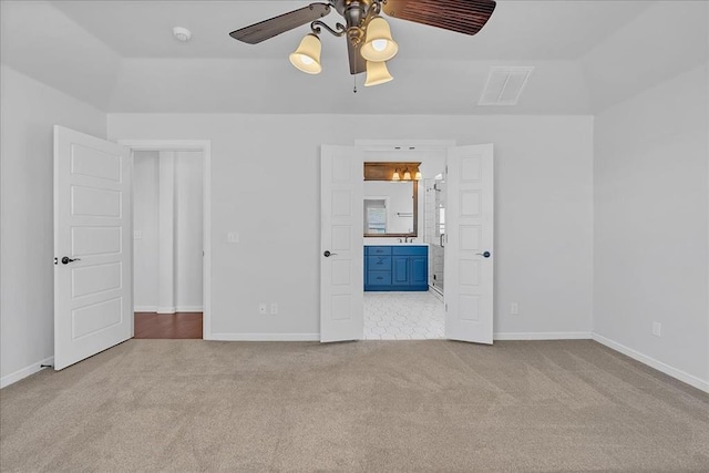 unfurnished bedroom featuring ensuite bath, light colored carpet, and ceiling fan