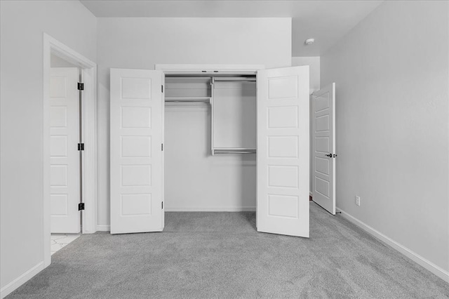 unfurnished bedroom featuring light carpet and a closet