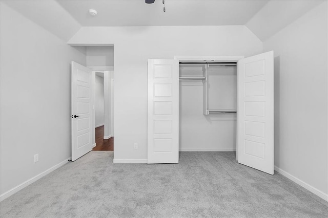 unfurnished bedroom with vaulted ceiling, light carpet, and a closet