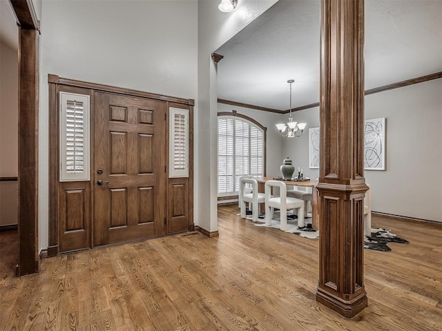 entrance foyer with an inviting chandelier, crown molding, light hardwood / wood-style flooring, and ornate columns