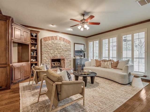 living room with hardwood / wood-style flooring, a stone fireplace, and a wealth of natural light