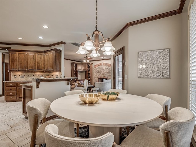 dining space featuring a notable chandelier, a fireplace, and ornamental molding