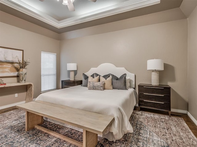 bedroom featuring dark hardwood / wood-style flooring, a tray ceiling, ornamental molding, and ceiling fan