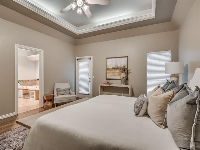 bedroom with a raised ceiling, hardwood / wood-style floors, and multiple windows