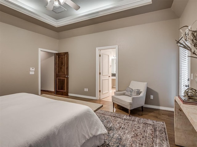 bedroom featuring hardwood / wood-style flooring, ensuite bath, and a tray ceiling