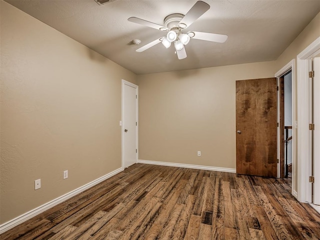 empty room with dark wood-type flooring and ceiling fan