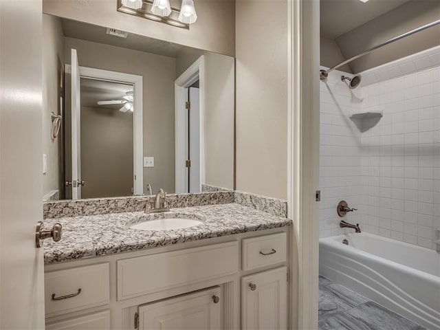 bathroom featuring ceiling fan, tiled shower / bath, and vanity