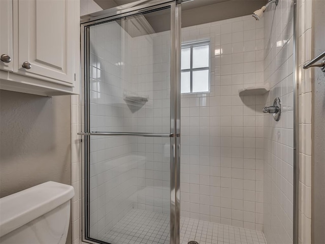 bathroom featuring toilet and a shower with shower door