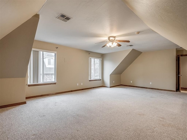 bonus room with ceiling fan, carpet flooring, vaulted ceiling, and a textured ceiling