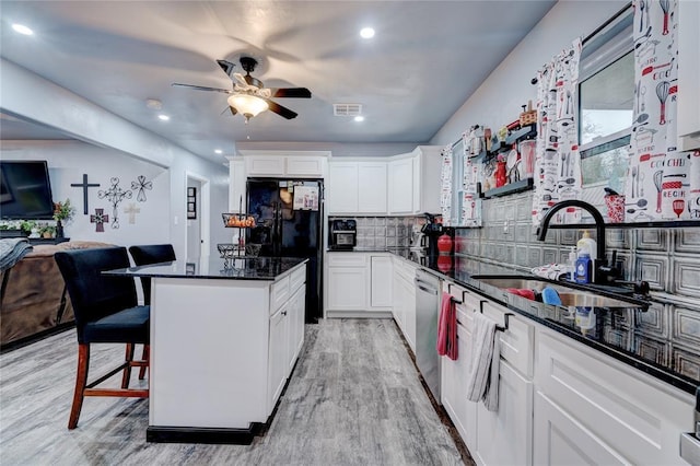 kitchen featuring dishwasher, black fridge, sink, and white cabinets