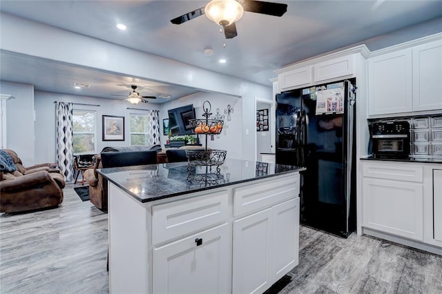 kitchen with black fridge, dark stone counters, light hardwood / wood-style floors, and white cabinets