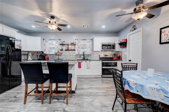 kitchen with decorative backsplash, stainless steel appliances, white cabinets, and a kitchen island