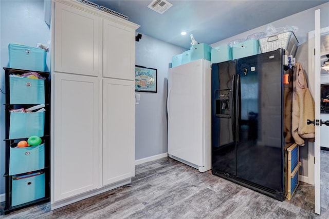 kitchen with white cabinetry, white fridge, light wood-type flooring, and black fridge with ice dispenser