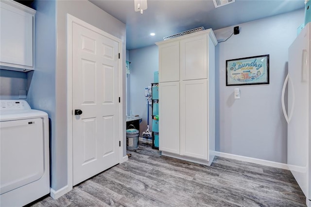 clothes washing area featuring washer / clothes dryer, light hardwood / wood-style flooring, and cabinets