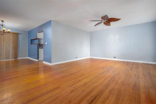 empty room with ceiling fan with notable chandelier and light hardwood / wood-style flooring