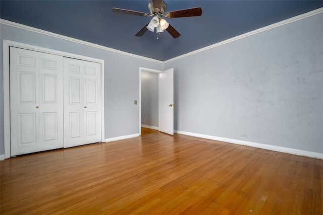 unfurnished bedroom featuring crown molding, hardwood / wood-style flooring, a closet, and ceiling fan