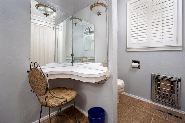 bathroom featuring toilet and heating unit