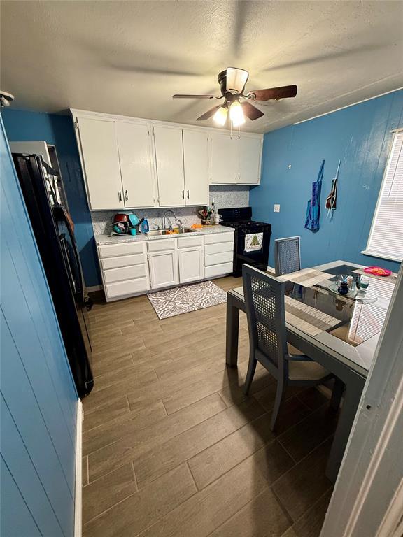 kitchen featuring hardwood / wood-style floors, white cabinetry, sink, backsplash, and black range