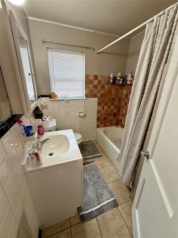 full bathroom featuring shower / tub combo with curtain, toilet, tile patterned flooring, and tile walls