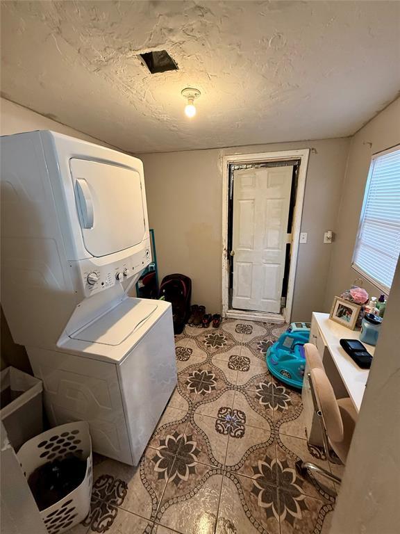 washroom with stacked washer and dryer and a textured ceiling