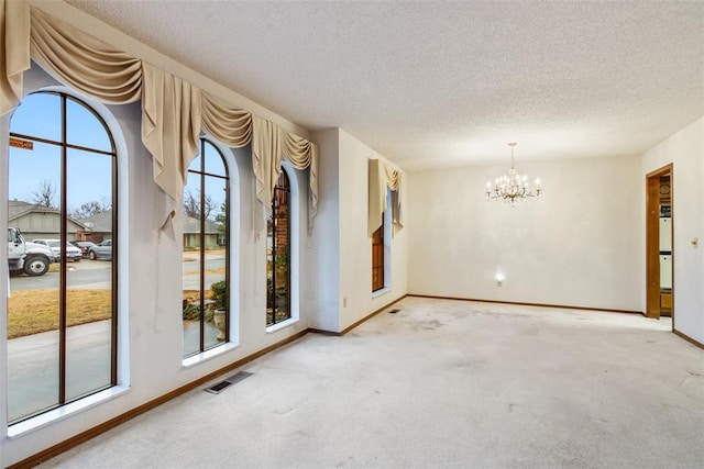 unfurnished room with an inviting chandelier, carpet, and a textured ceiling